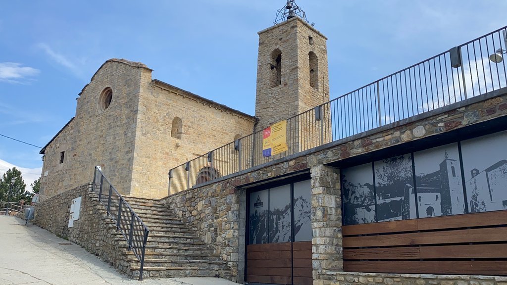 Pla obert on es veu l'entrada del Centre d'Interpretació del país dels Esterregalls i l'església de Santa Maria d'All, a Isòvol (Cerdanya). Imatge del 8 d'abril de 2021 (Horitzontal).